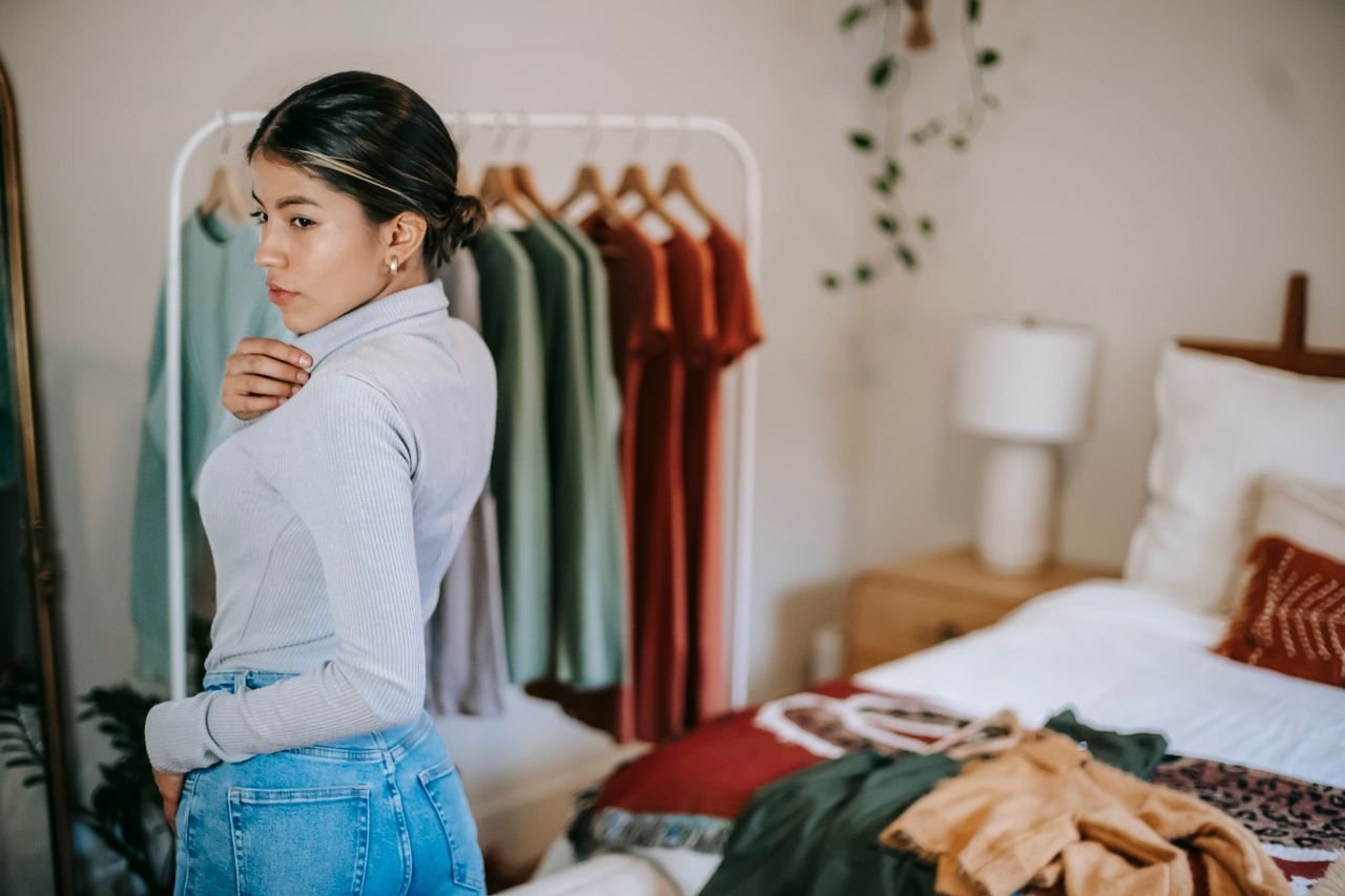 Mastering the First Impression: Your intriguing post title goes here Side view of confident ethnic woman in trendy outfit demonstrating outfit in bedroom near bed and wardrobe near mirror at home